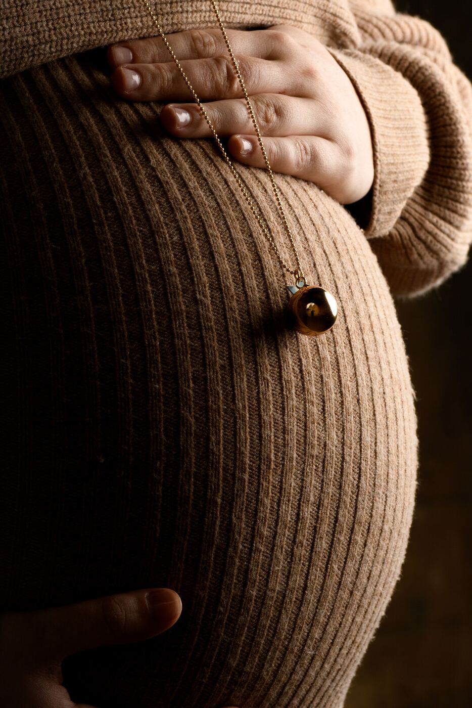 Séance grossesse : mains posées sur un ventre rond